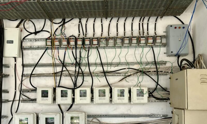 Complex network of electrical wiring and control panels in an industrial setting.
