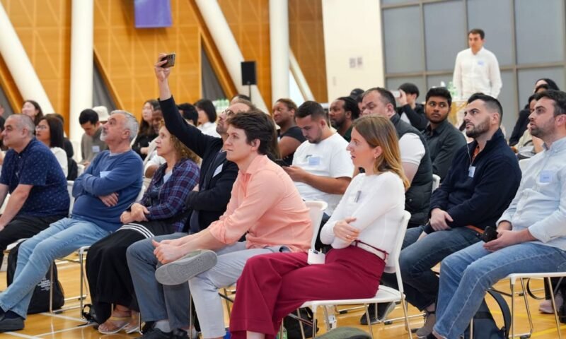 A diverse audience attentively listens during an indoor seminar, showcasing a collaborative learning environment.