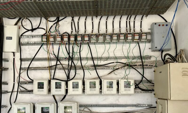 Complex network of electrical wiring and control panels in an industrial setting.